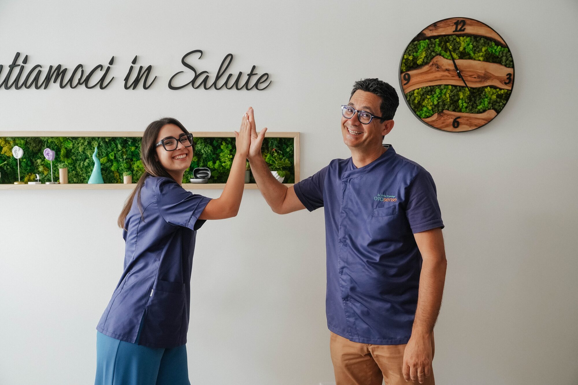 Dott. Gino Flamingo e Dott.ssa Aurora Randone davanti al claim 'Sentiamoci in Salute' nello studio Otosense.